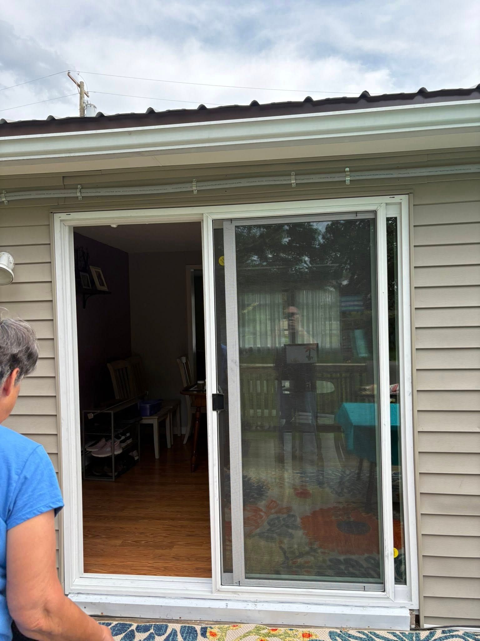 Sliding glass door with screen, open to interior, person standing to left.