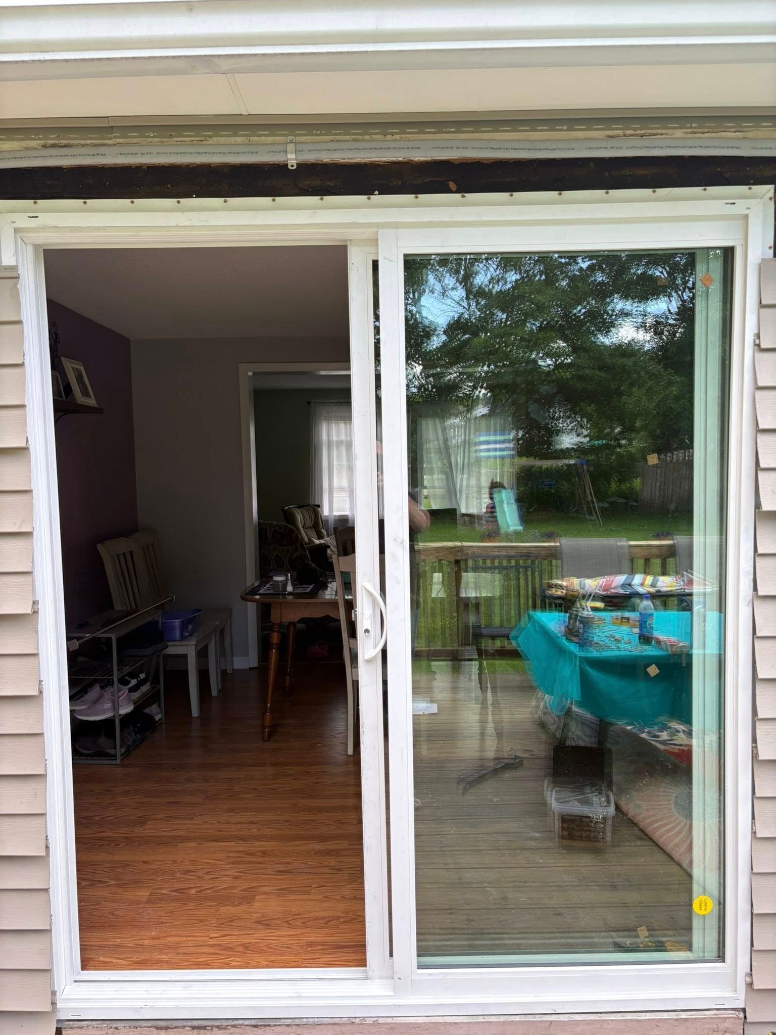 Sliding glass door, one panel open, showing interior and exterior views. Wood siding.