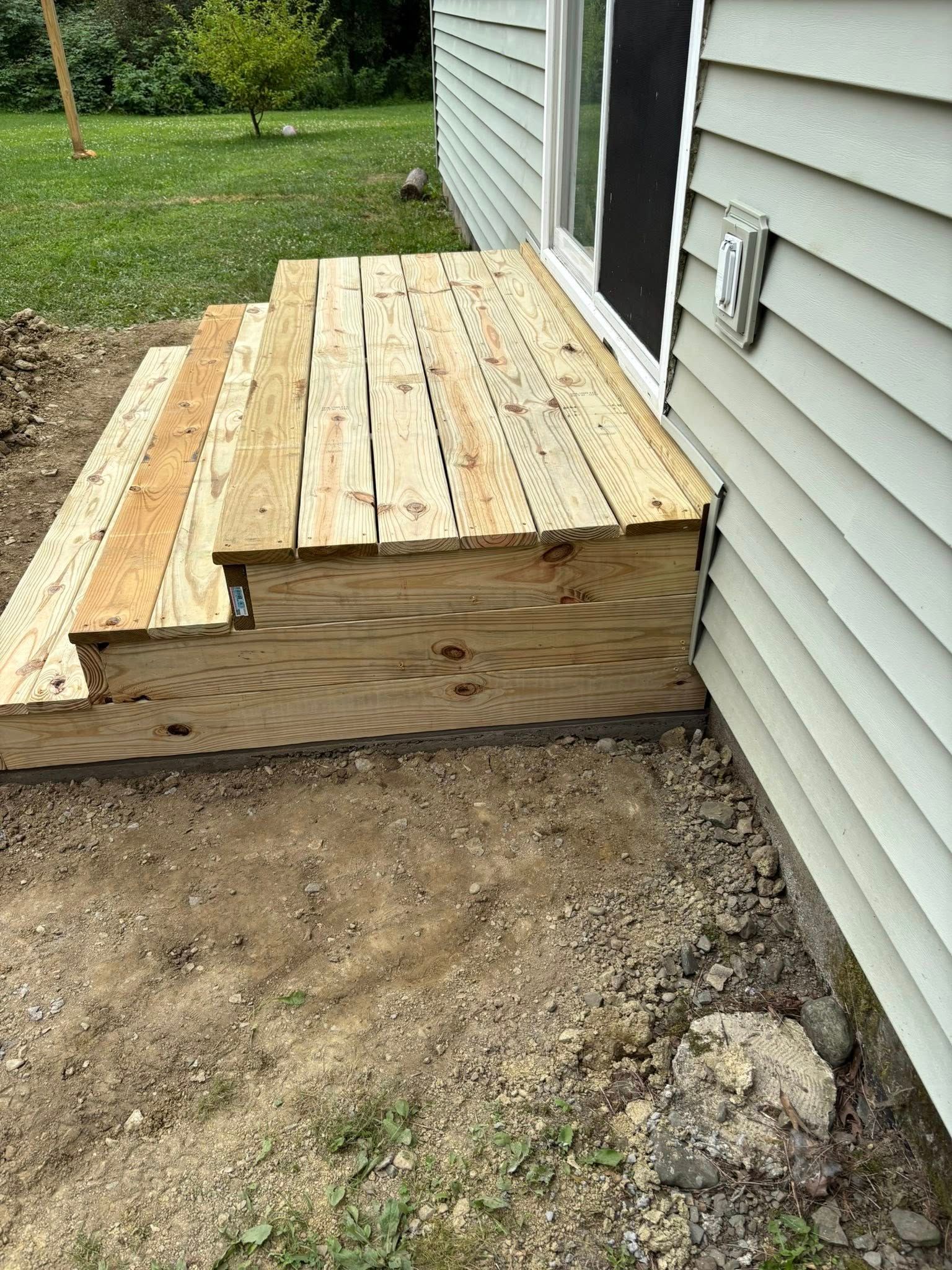 Wooden deck steps next to a house with a sliding glass door.