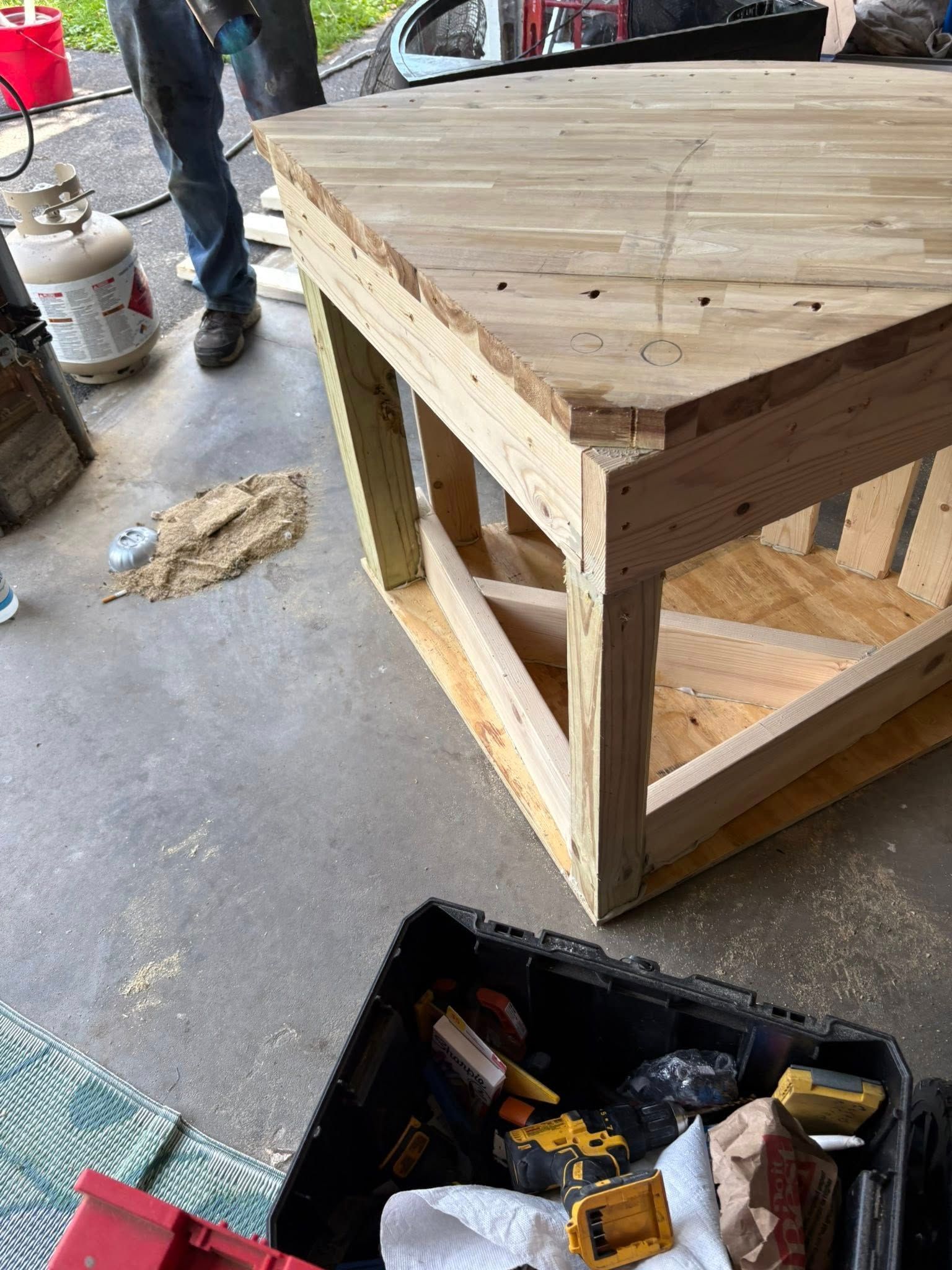 Workbench construction: Wooden frame with a finished top; tools and propane tank in the setting.