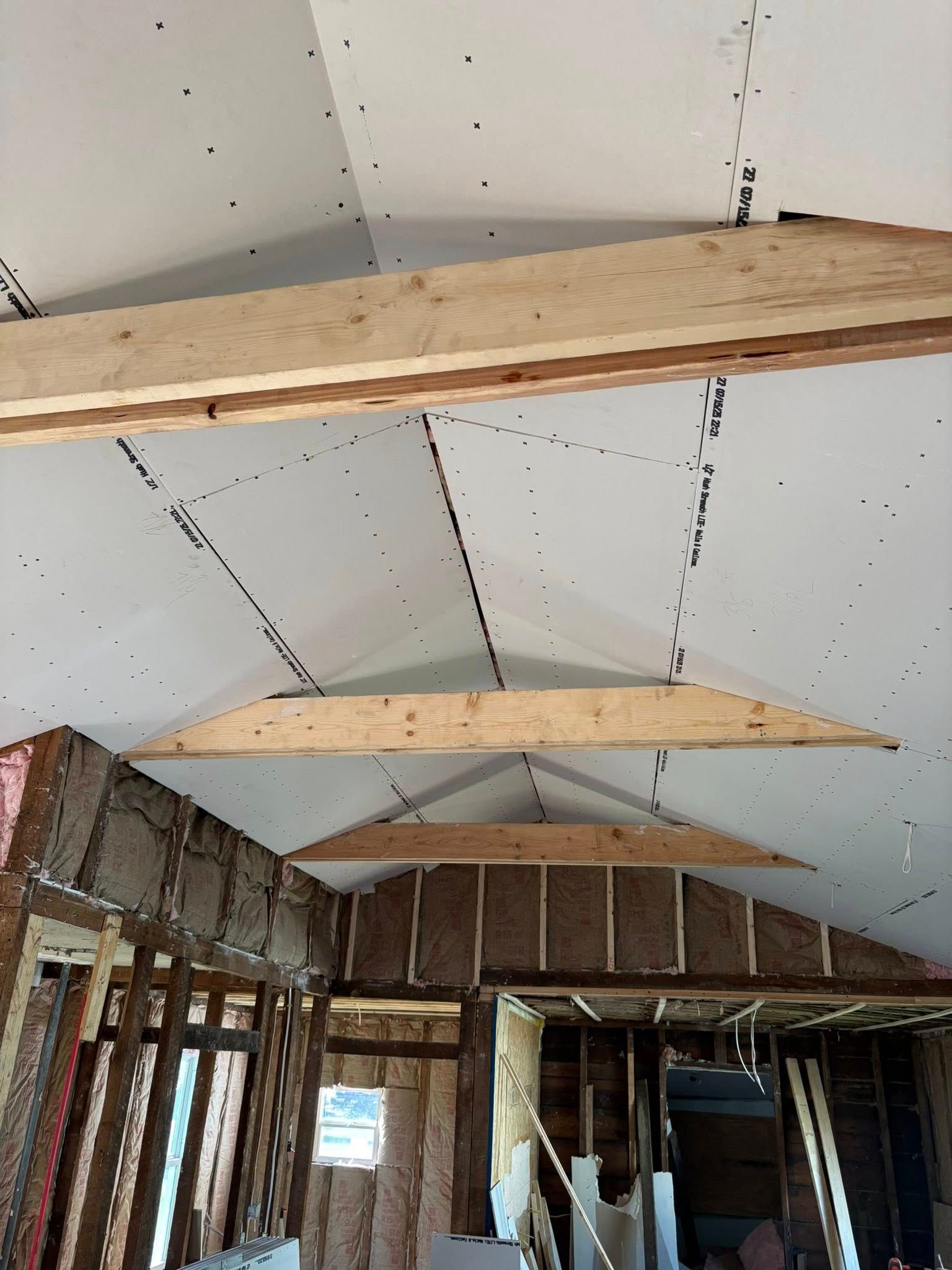 Interior of a building under construction. Exposed beams and insulation visible with drywall in place.