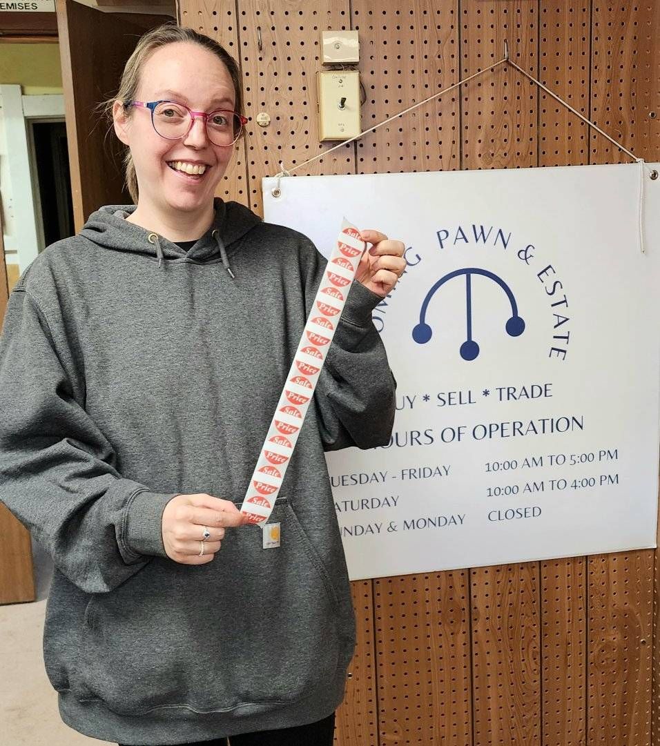A woman is holding a measuring tape in front of a sign that says paws 4 estate