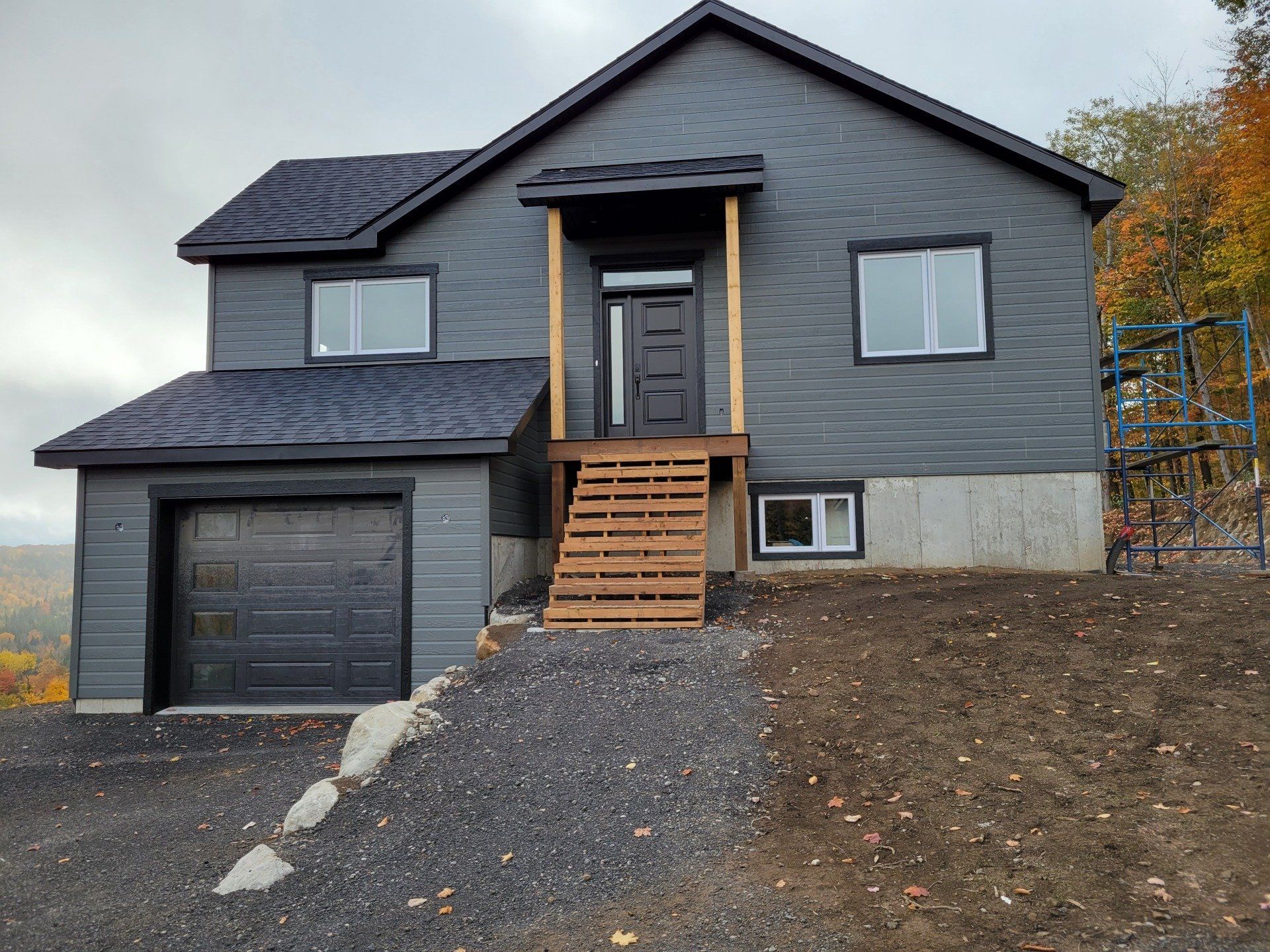 Une maison noire est assise au sommet d'une colline de terre.