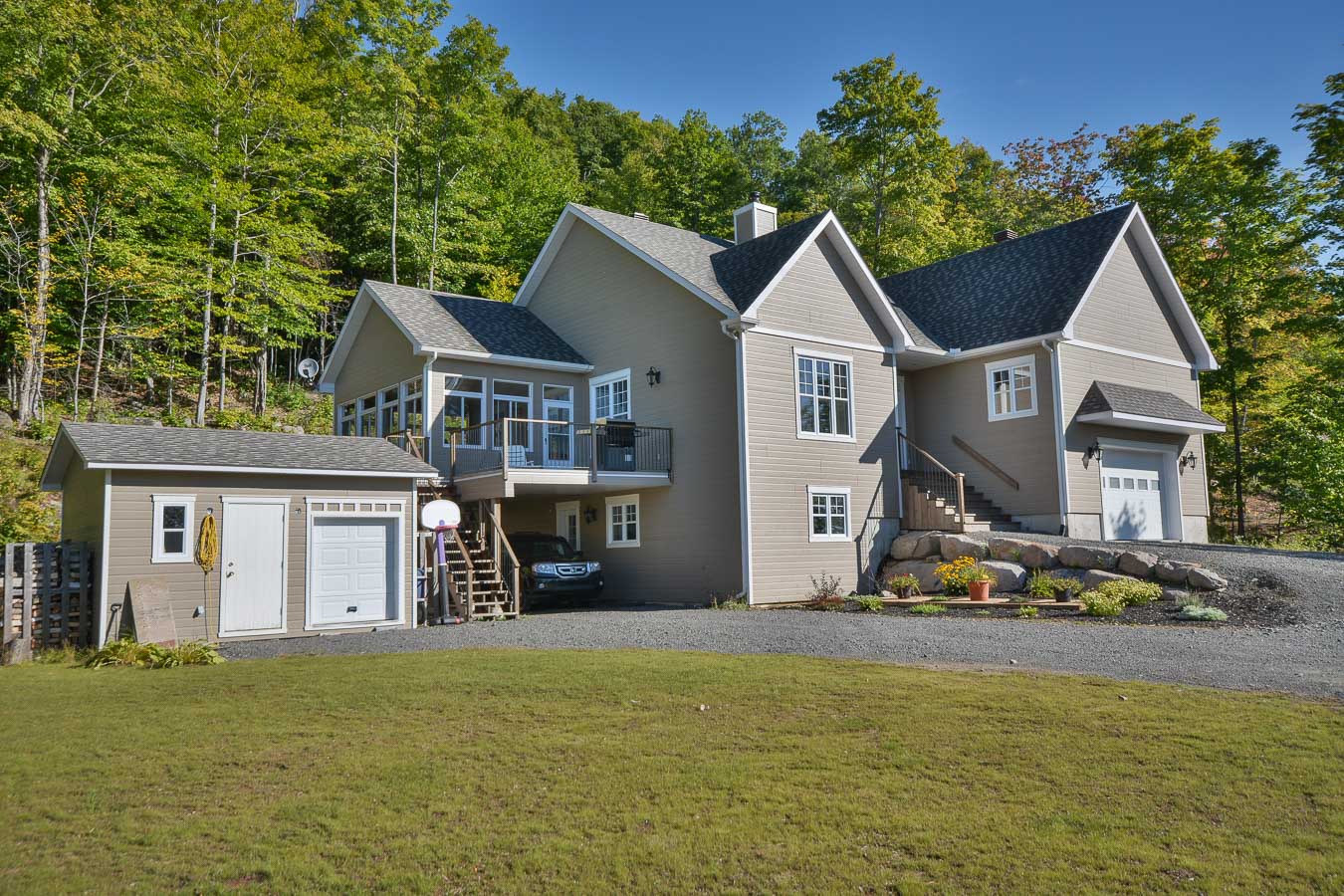 Une grande maison avec un garage est entourée d'arbres.