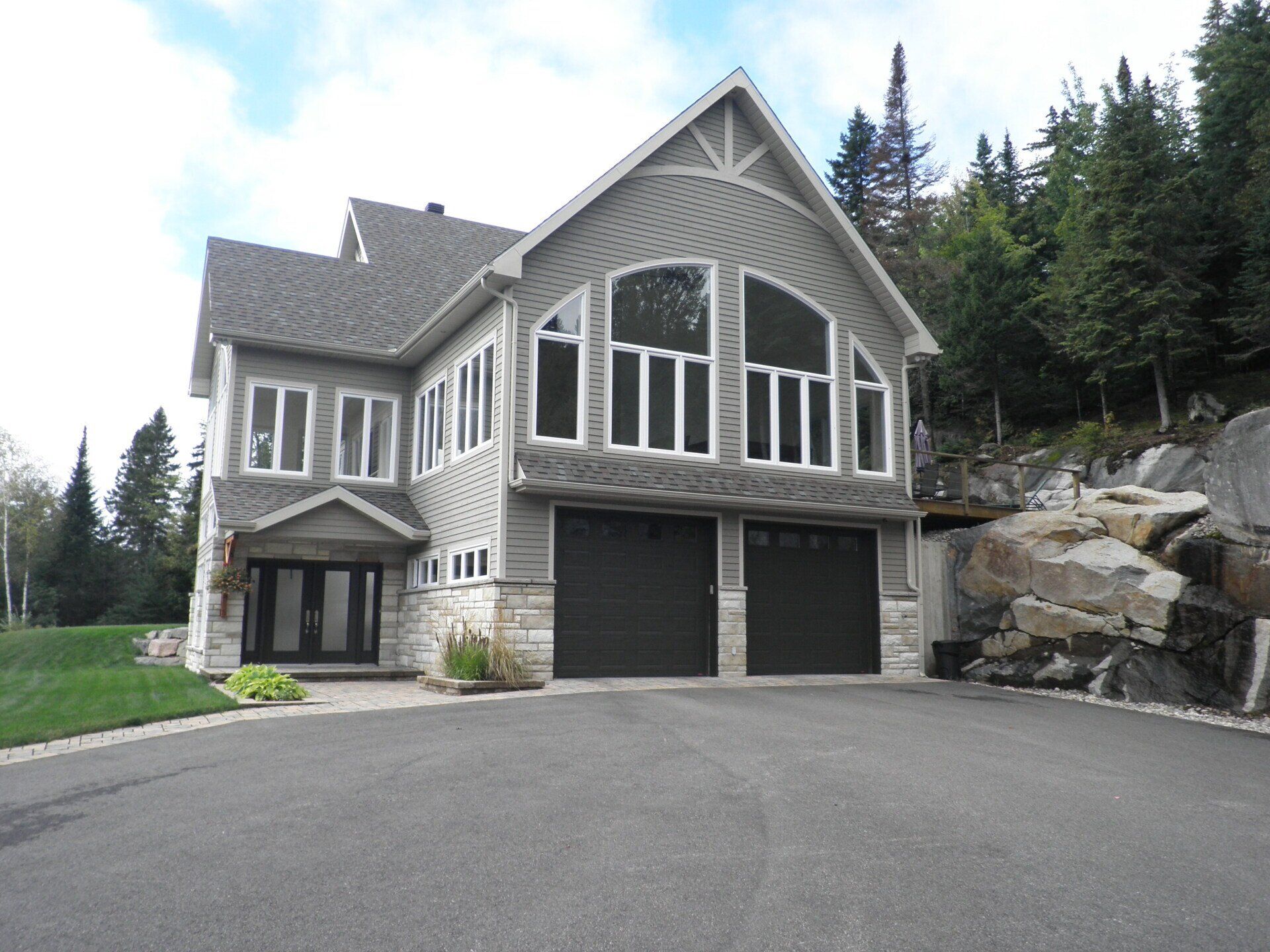 Une grande maison avec beaucoup de fenêtres et des portes de garage noires