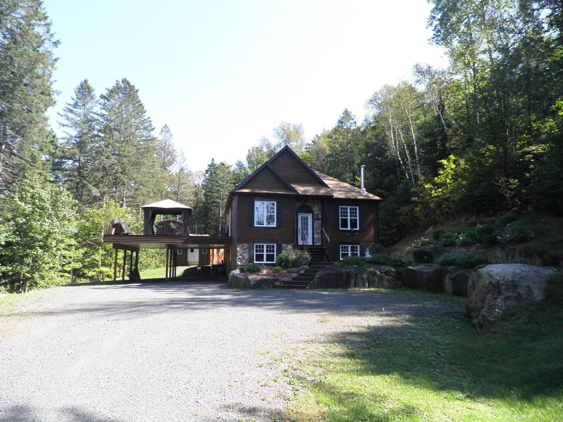 Une grande maison est entourée d'arbres et d'une allée de gravier