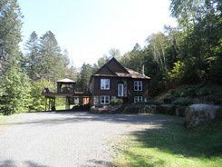 Une grande maison est située au sommet d'une colline au milieu d'une forêt.