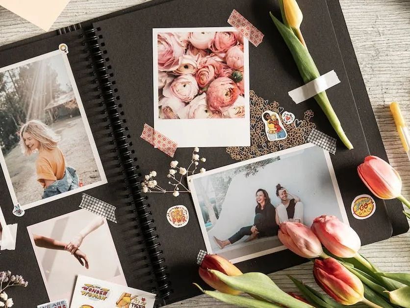 A photo album filled with pictures and flowers on a table.