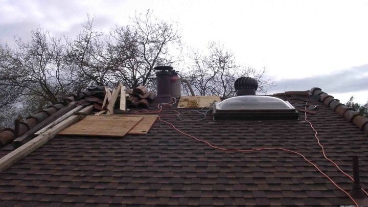 A roof with a chimney and a skylight on it.
