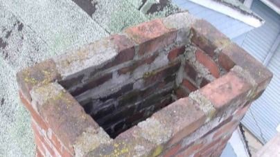 A brick chimney is sitting on top of a roof.