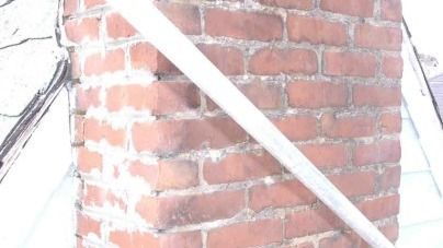 A brick chimney with a white pipe sticking out of it.