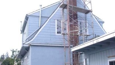 A house with a chimney on the side of it and scaffolding around it.