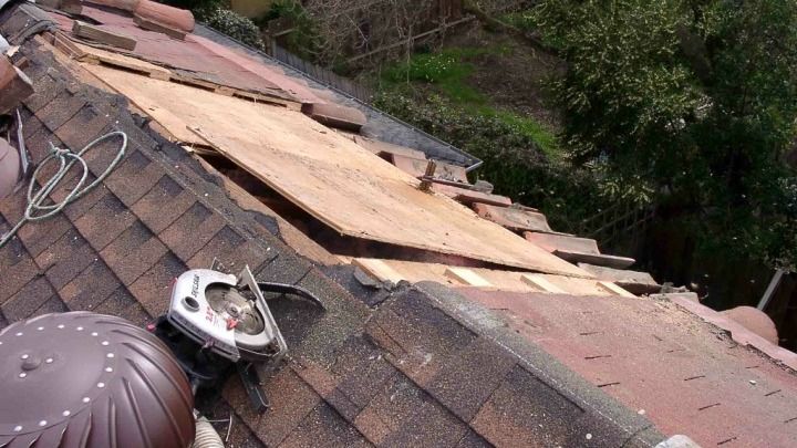 A roof with a hole in it is being repaired.