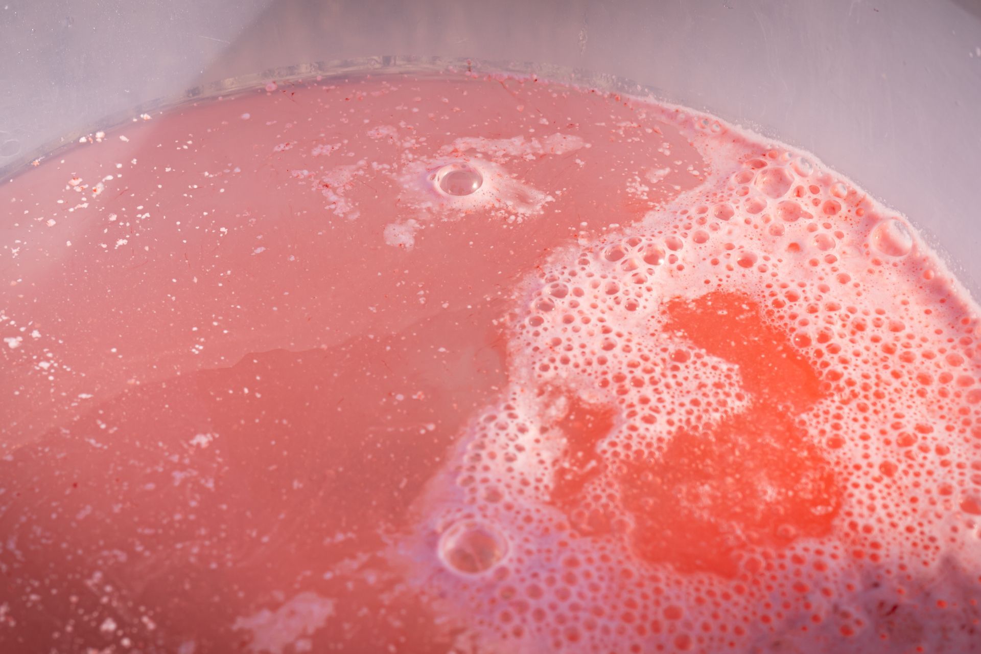 A close up of a pink liquid with bubbles in it.