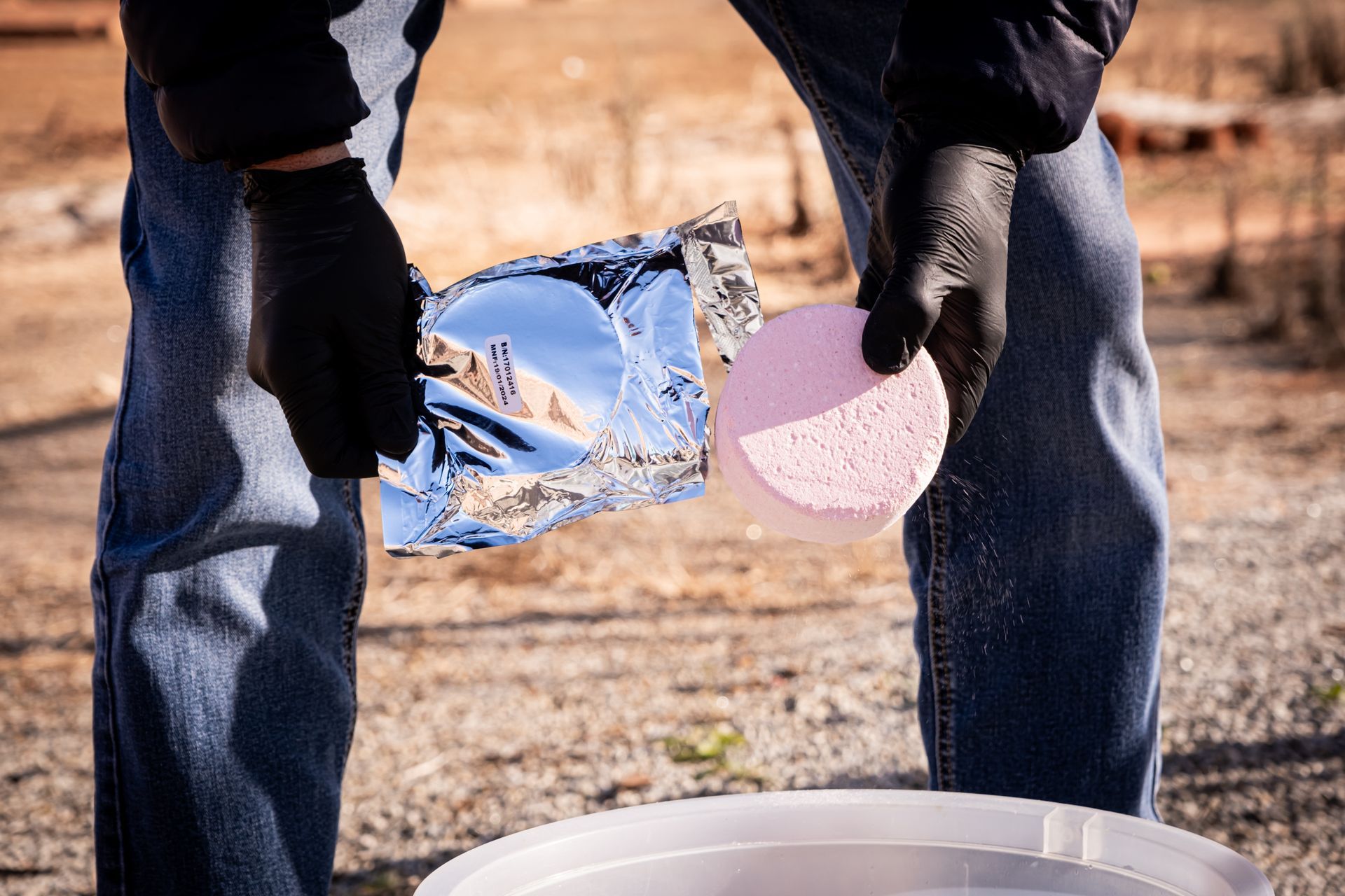 A person is pouring something from a bag into a bucket.
