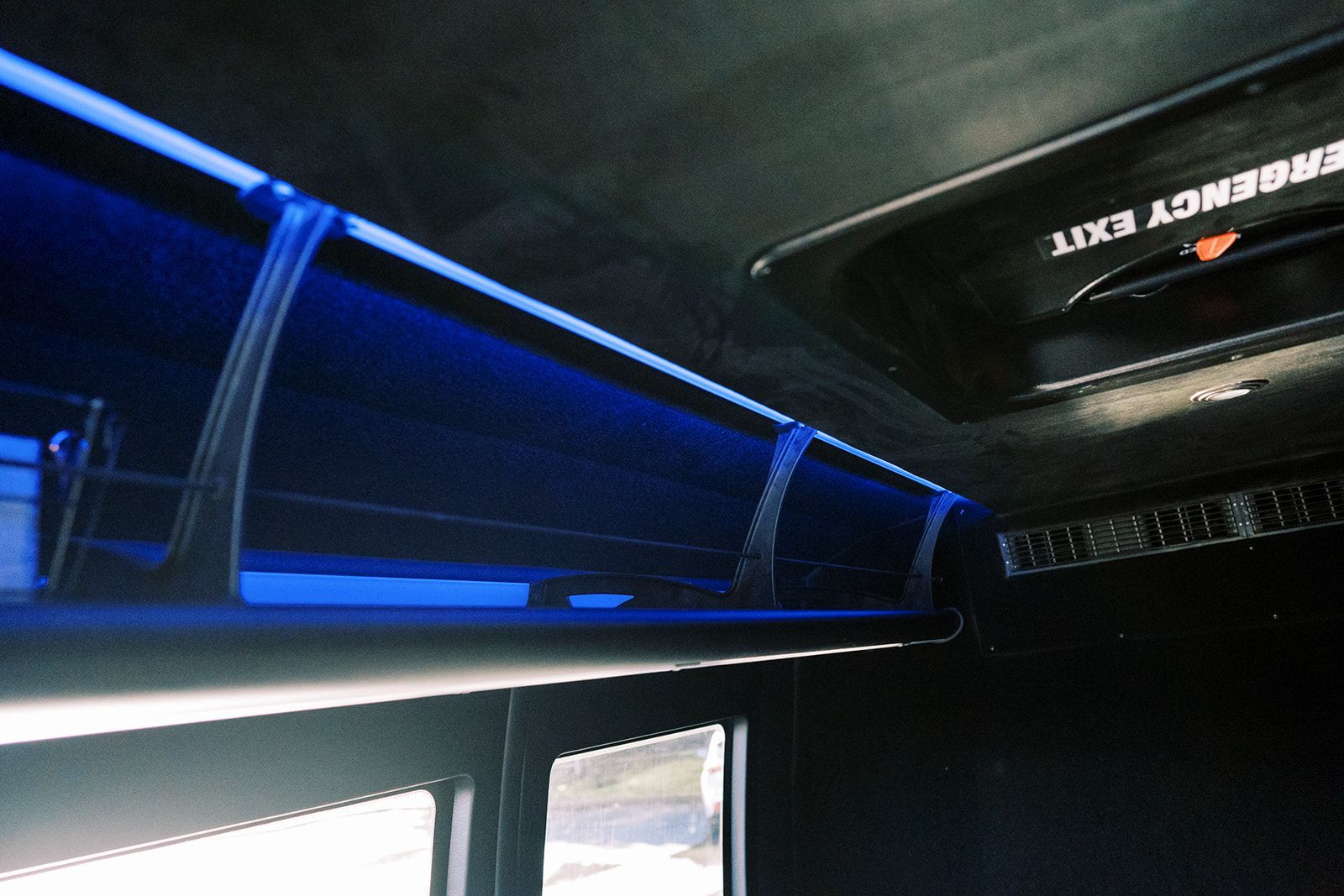 An emergency exit sign on the ceiling of a bus