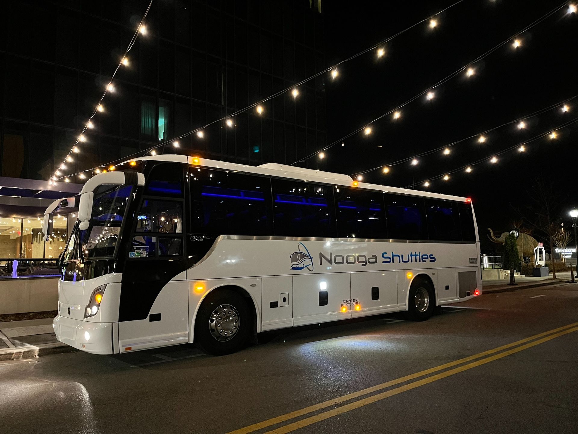 A large white bus is parked in front of a building