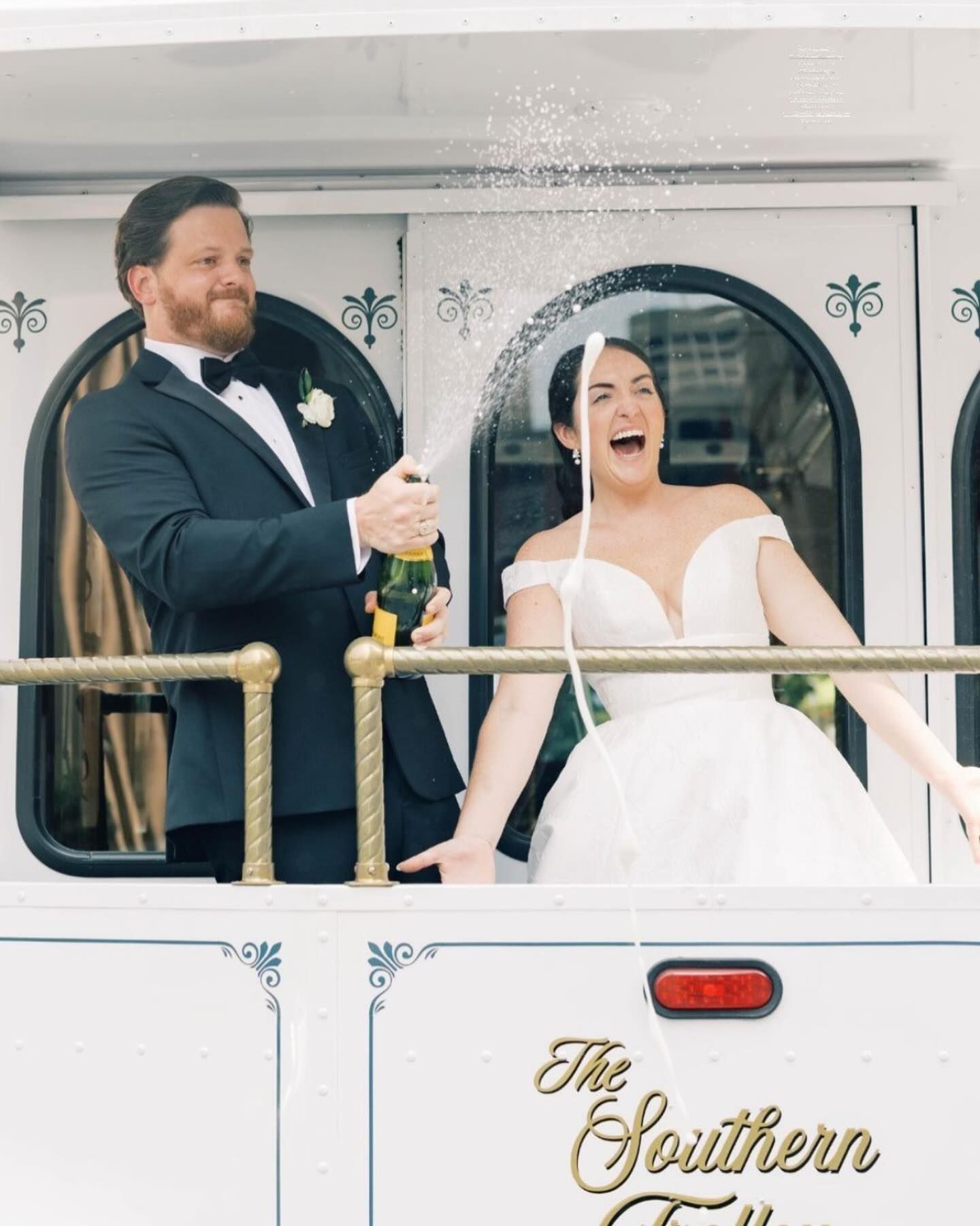 A bride in a wedding dress is standing next to a black van.