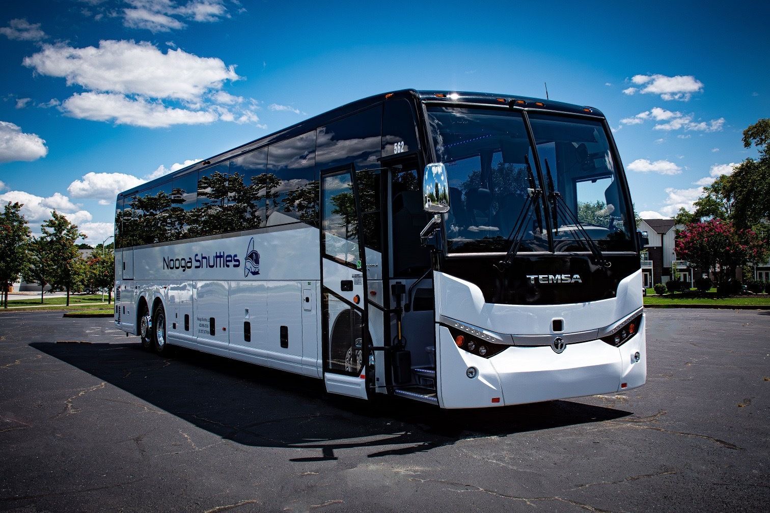 A white bus is driving down a highway under a bridge.