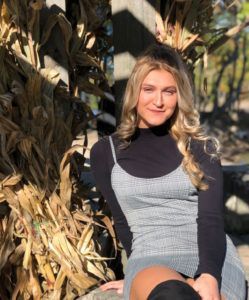 a woman in a gray dress is sitting in front of a corn field .