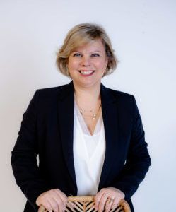 a woman in a black jacket and white shirt is sitting in a chair .