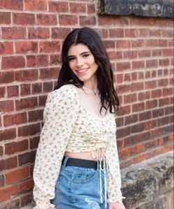 a woman in a crop top and shorts is standing in front of a brick wall .