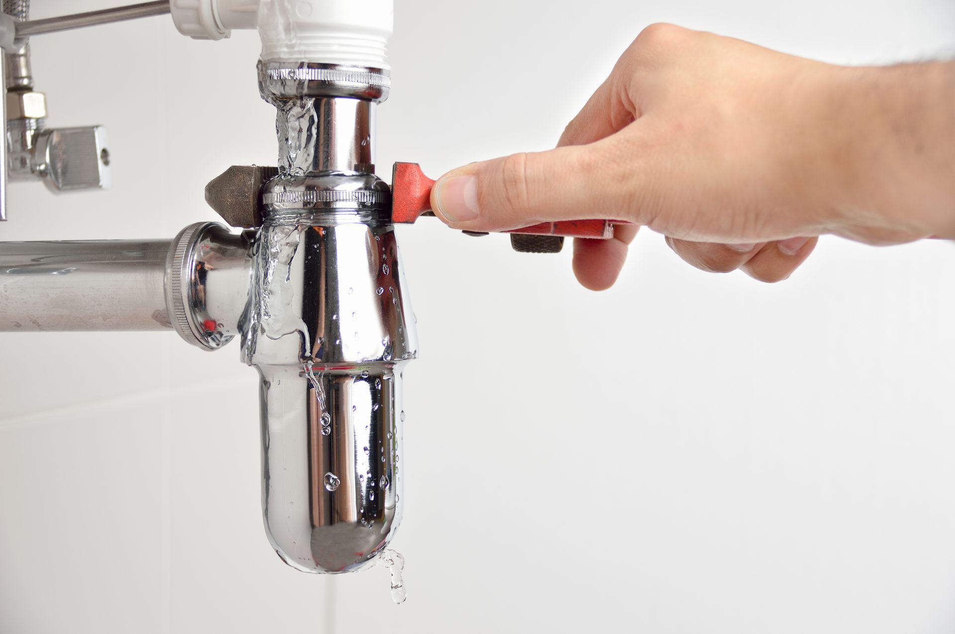 A person is fixing a sink pipe with a wrench.