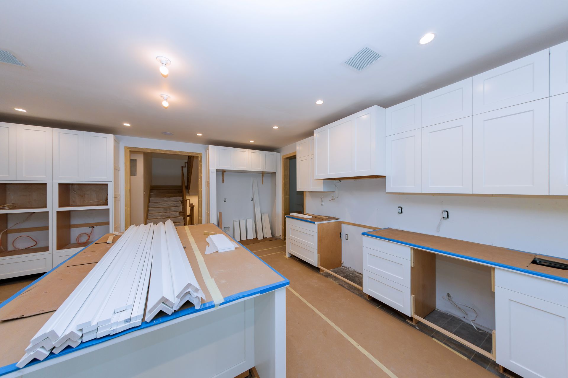 A kitchen under construction with white cabinets and a table.