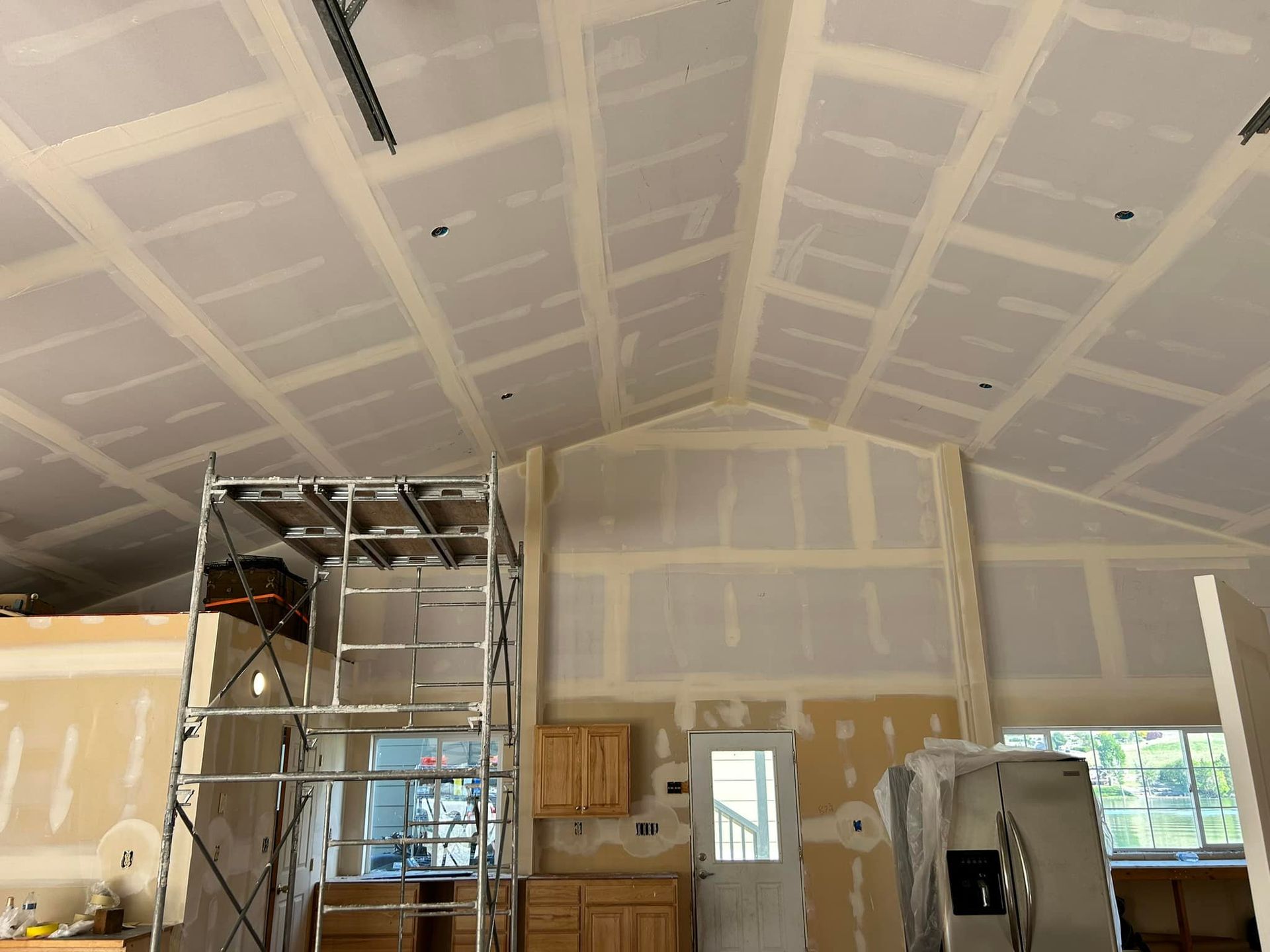 A room with a vaulted ceiling and a ladder in the middle of it.