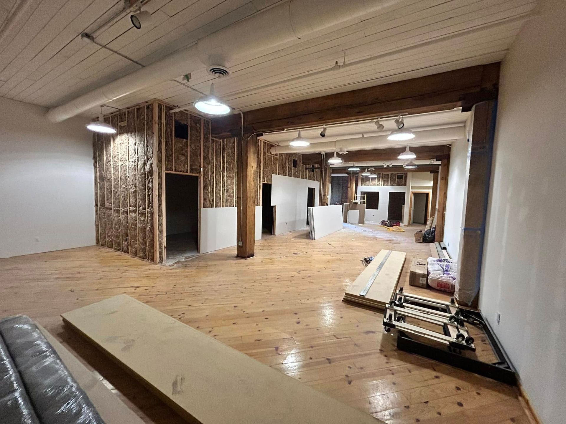 A large empty room with a wooden floor and a ladder.