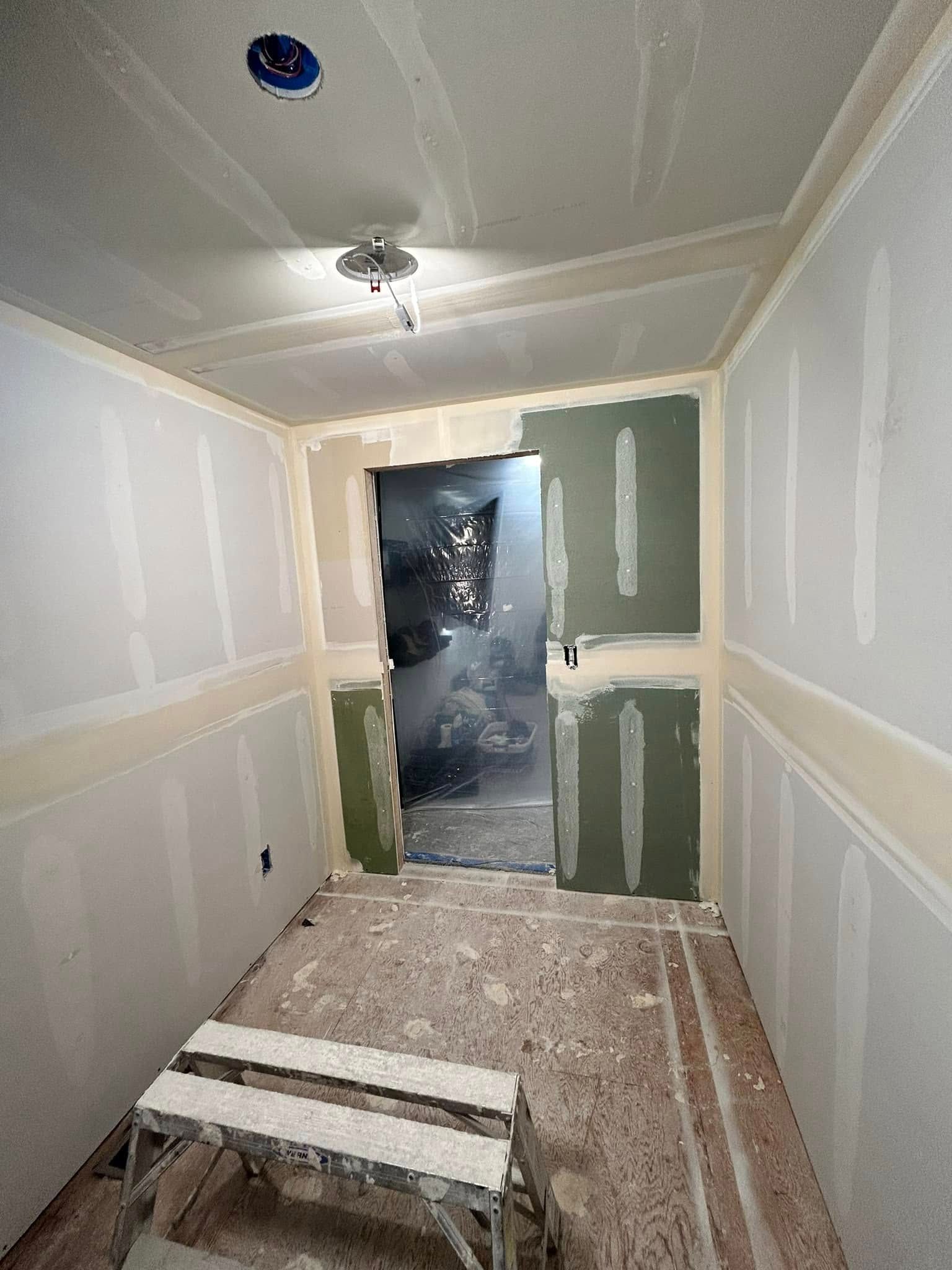 A room with a door and a ladder in it is being remodeled.