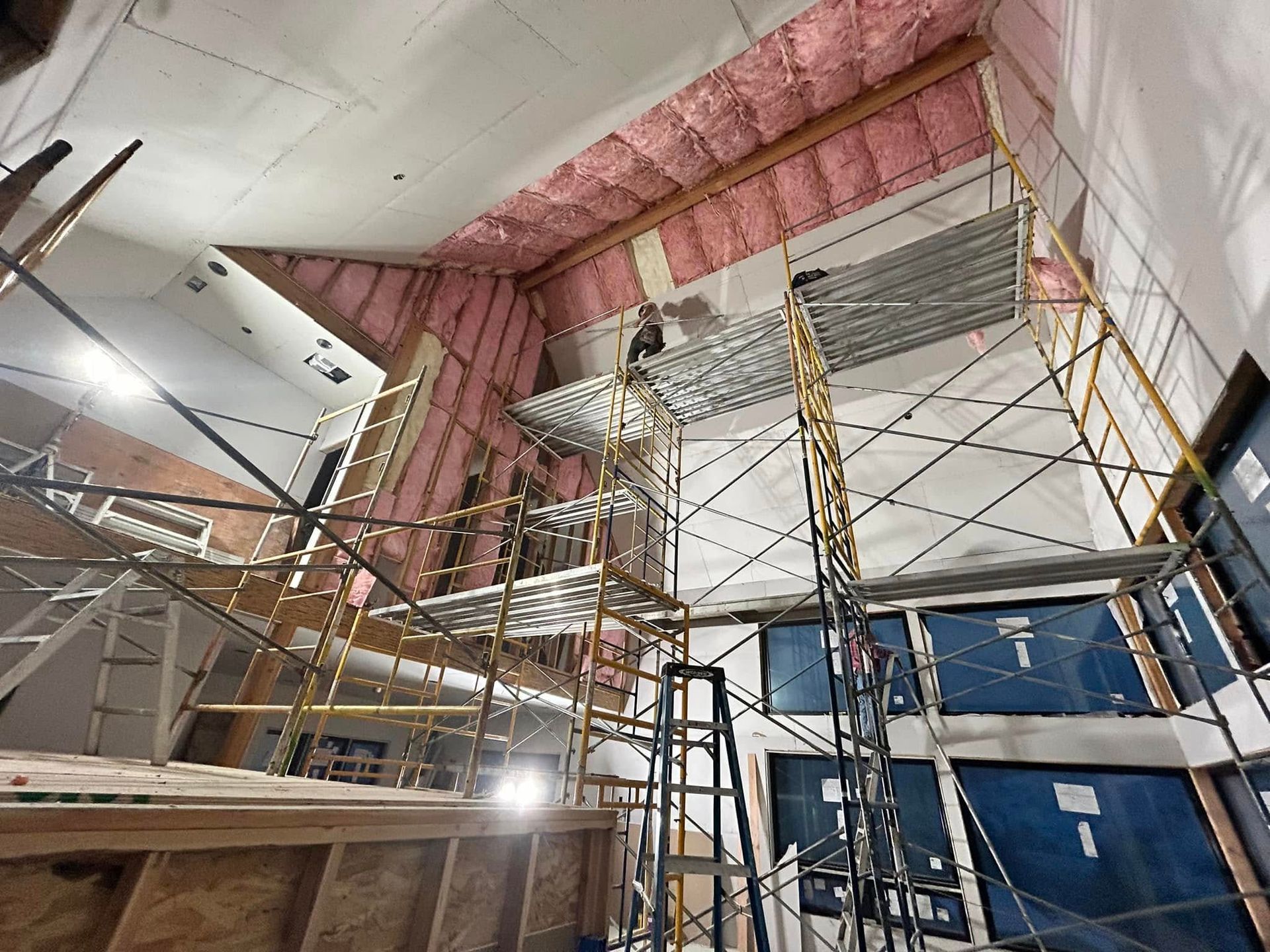 A building under construction with scaffolding and insulation on the ceiling.