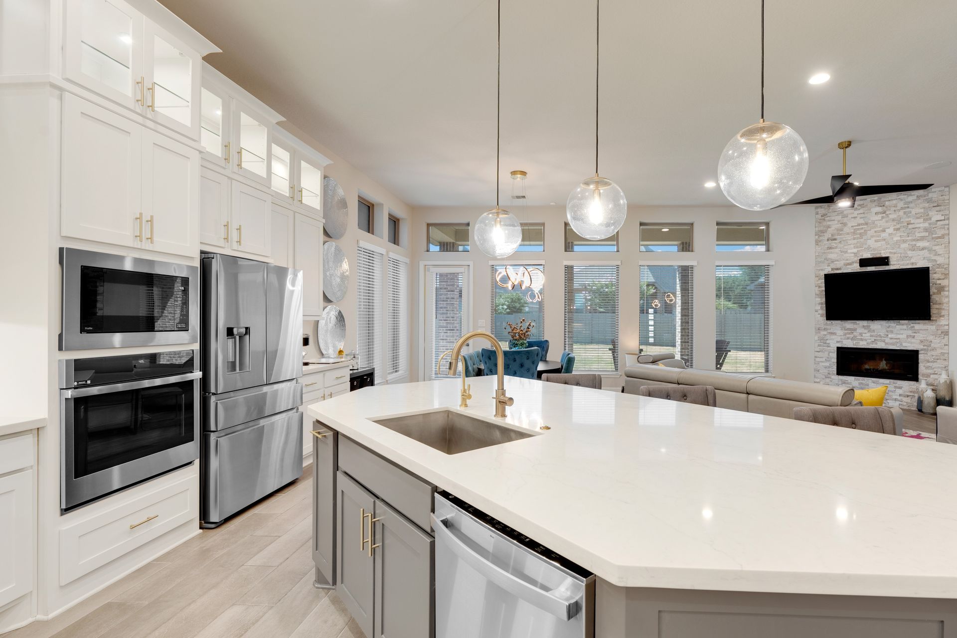 A kitchen with white cabinets , stainless steel appliances , a large island , a sink and a refrigerator.