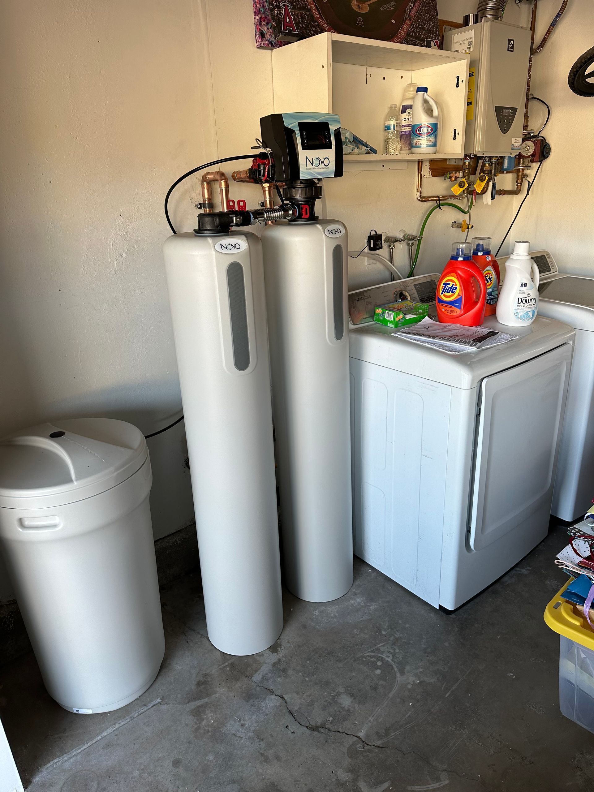Water softener and filtration system next to a washing machine in a garage.