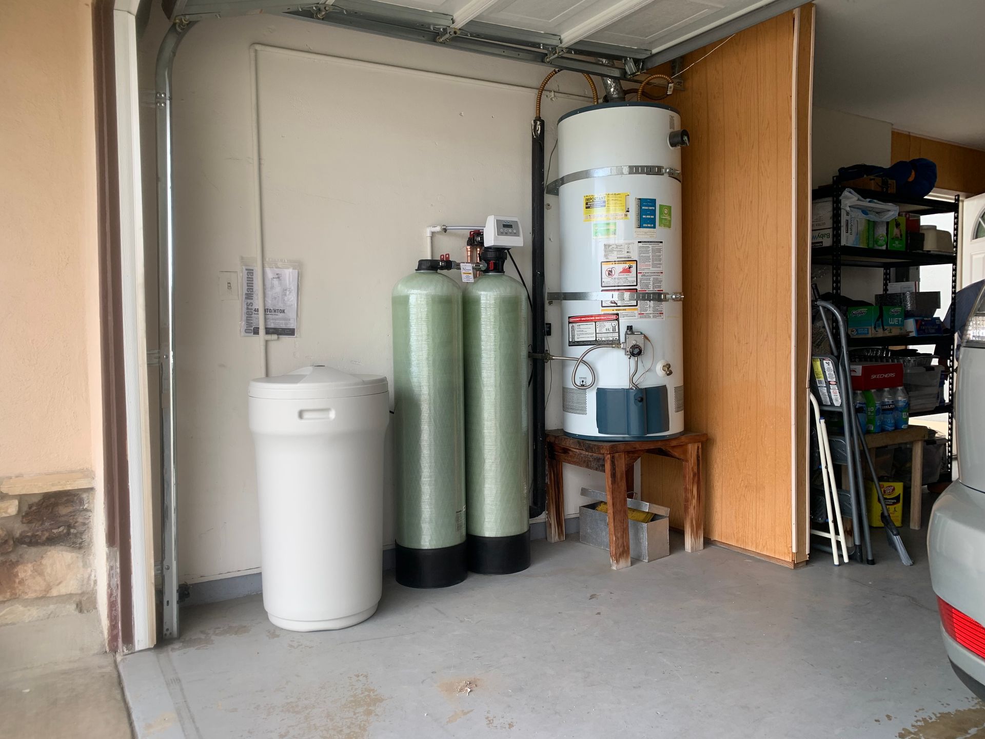 Garage interior with water softener and heater, alongside a storage rack.