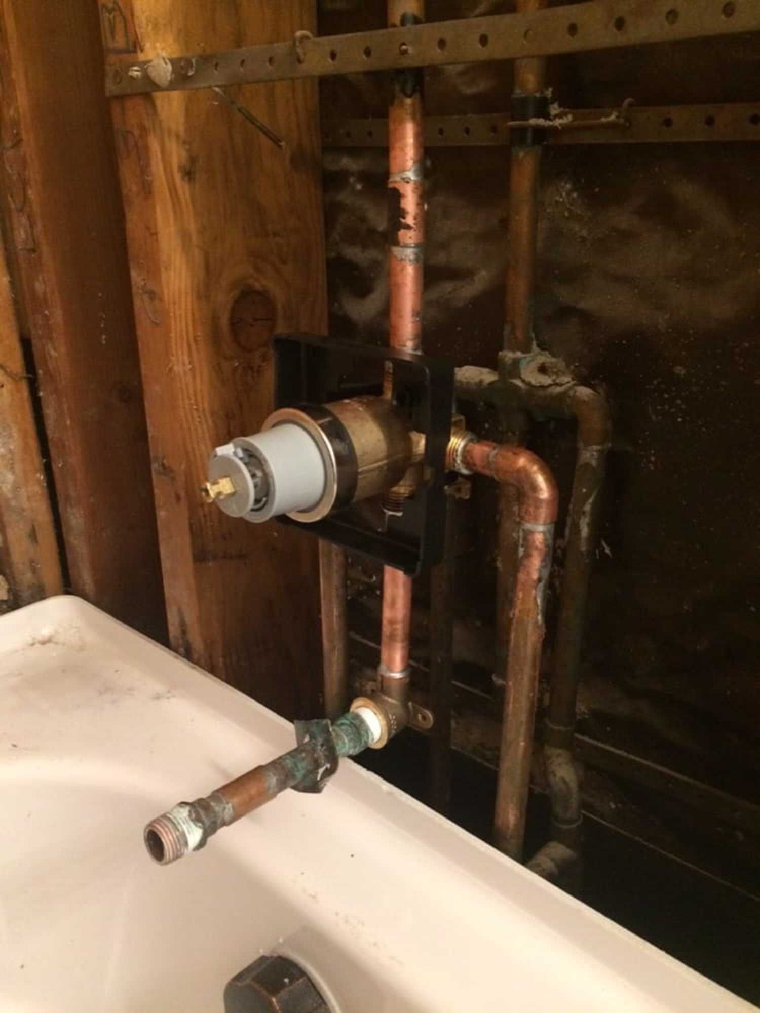 A bathroom sink with copper pipes and a faucet.