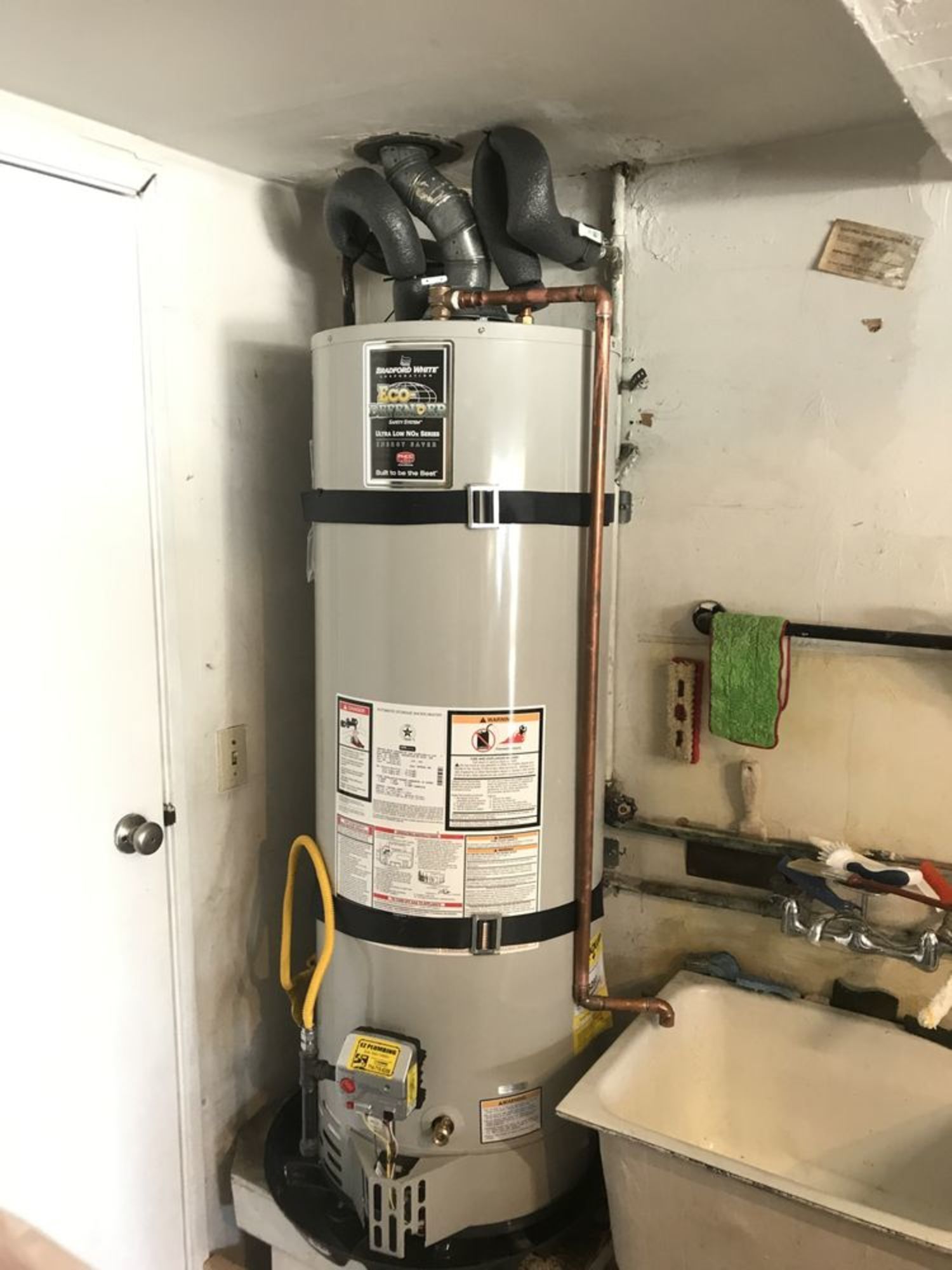 A water heater is sitting in a room next to a sink.