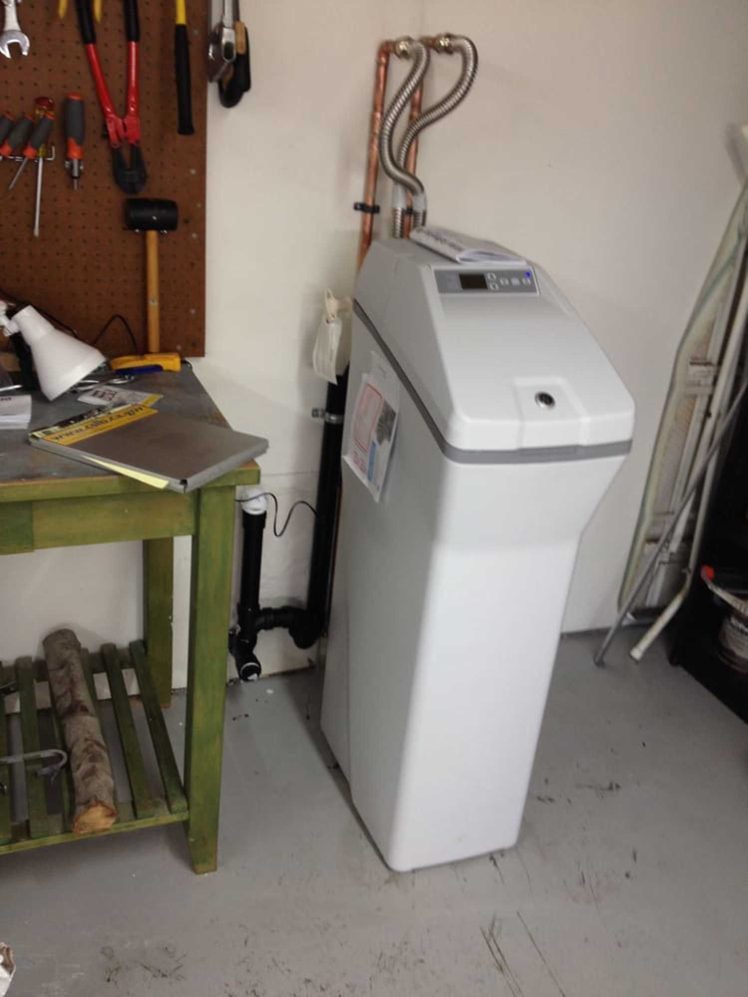 A water softener is sitting next to a wooden table