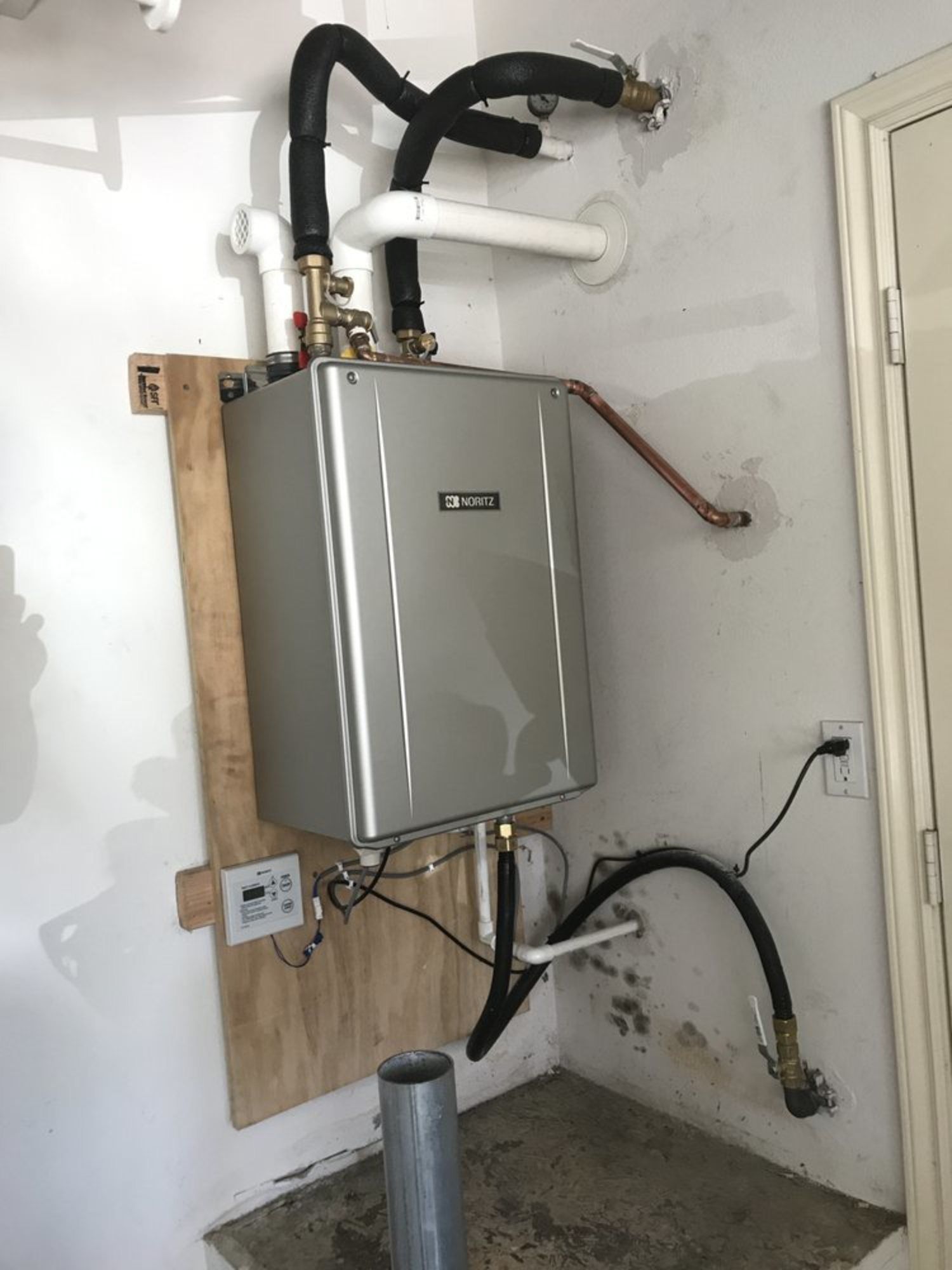 A water heater is mounted to the wall in a room.