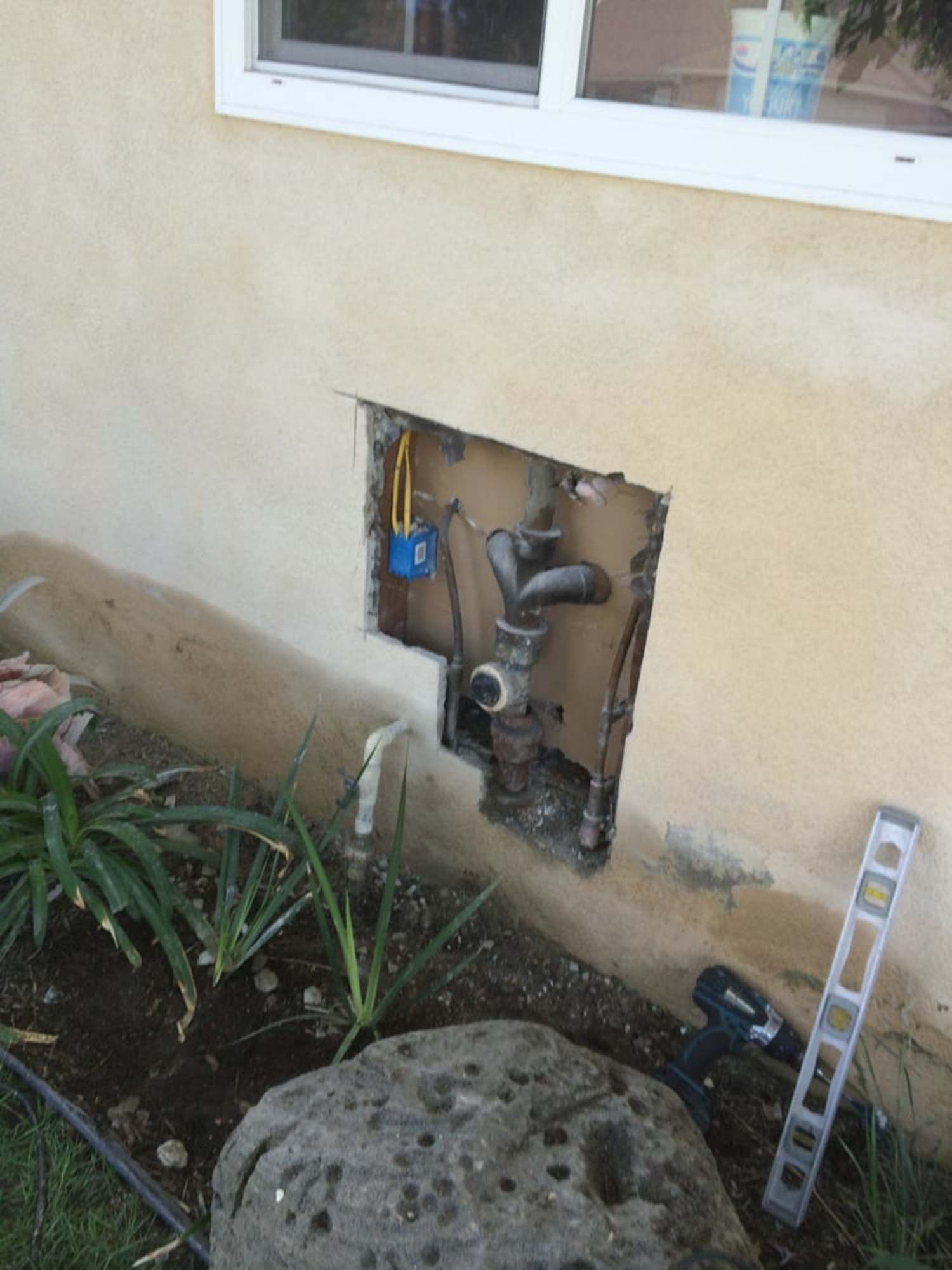 A hole in the wall of a house with pipes coming out of it.