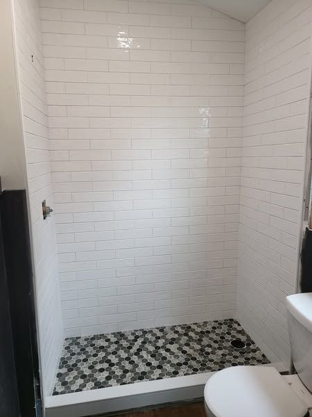 A bathroom with a walk in shower and a toilet.