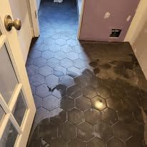 A black tile floor in a hallway next to a door.