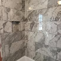 A bathroom with marble tiles and a bathtub.