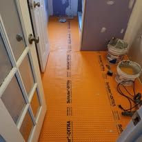 A hallway with orange flooring and buckets of paint.