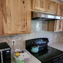A kitchen with a stove , microwave , and wooden cabinets.