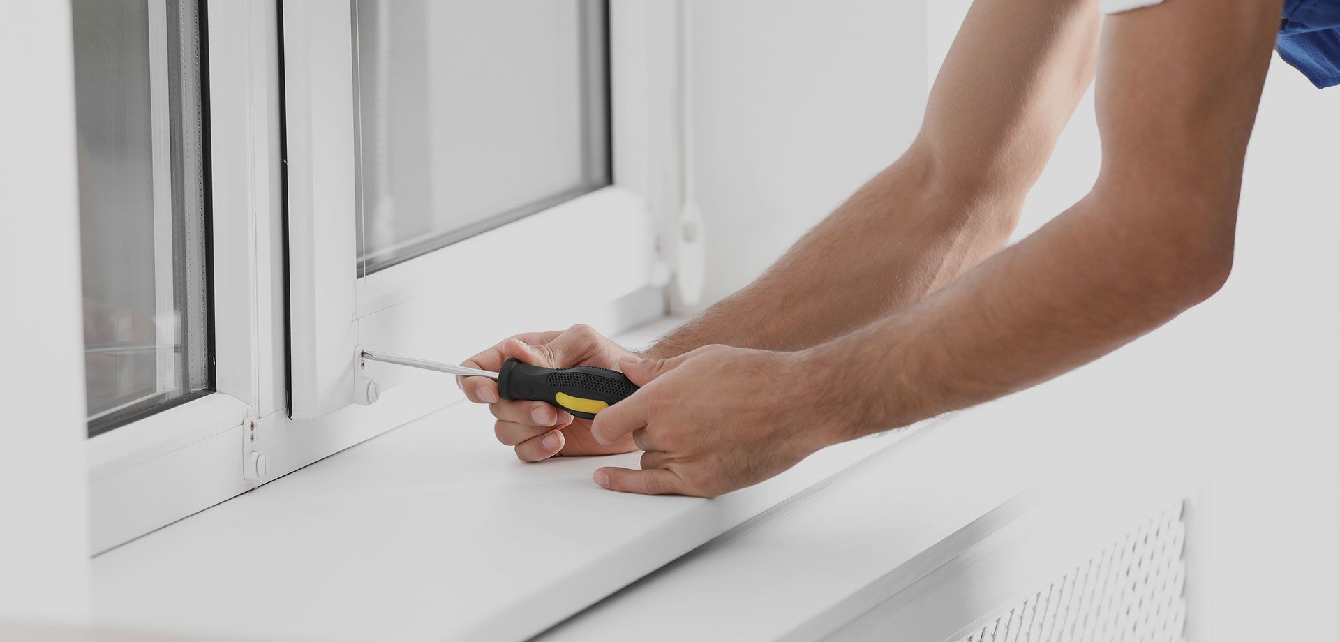 A man is fixing a window with a screwdriver.