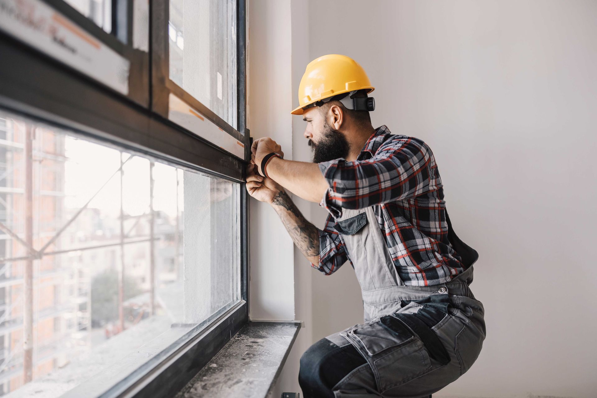 A man in a hard hat is installing a window.