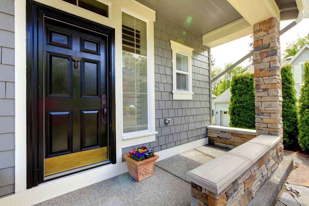 The front door of a house with a black door and a porch.