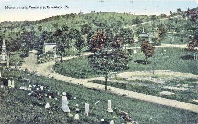 A black and white photo of a cemetery with a church in the background