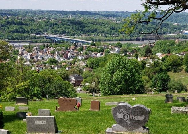 A cemetery with a bridge in the background and a city in the distance